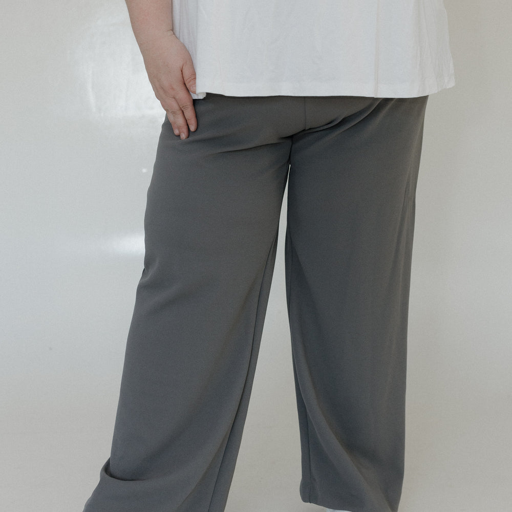 Person wearing a white top and gray wide-leg pants on a plain background