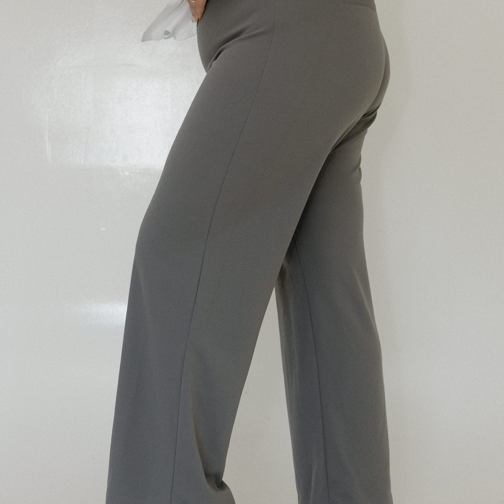 Person wearing gray pants and white shoes on a plain background
