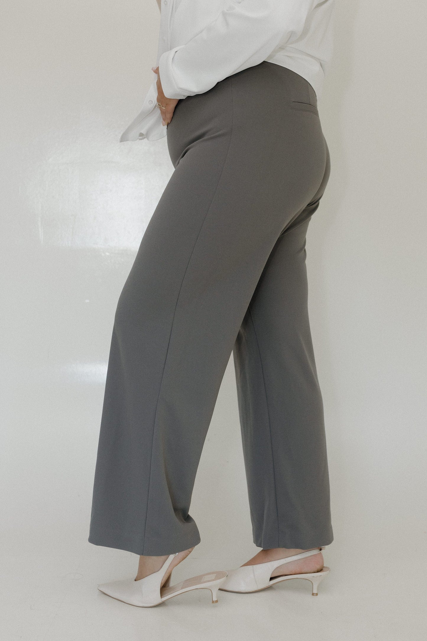 Person wearing gray pants and white shoes on a plain background