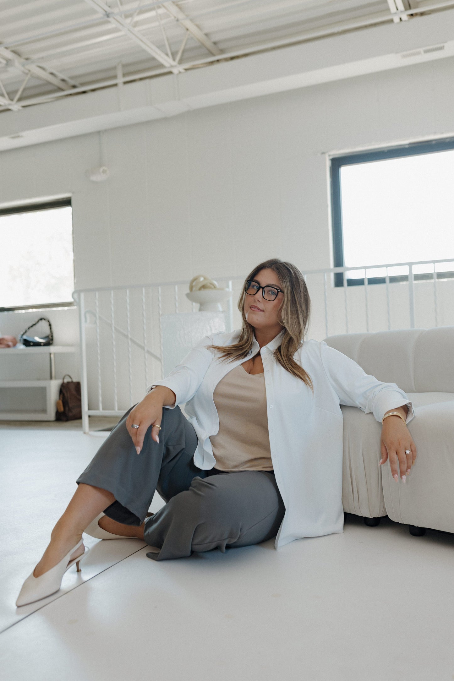 Woman sitting on a white couch in a modern office setting