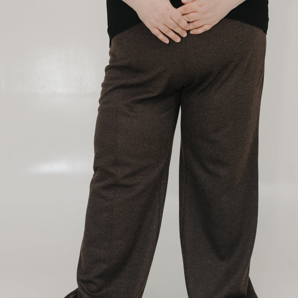 Person wearing brown wide-leg pants and a black top on a white background