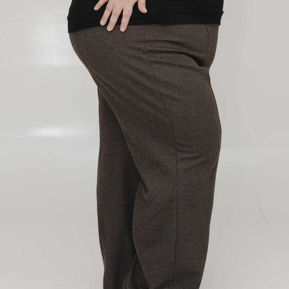 Person wearing brown pants and a black top on a white background