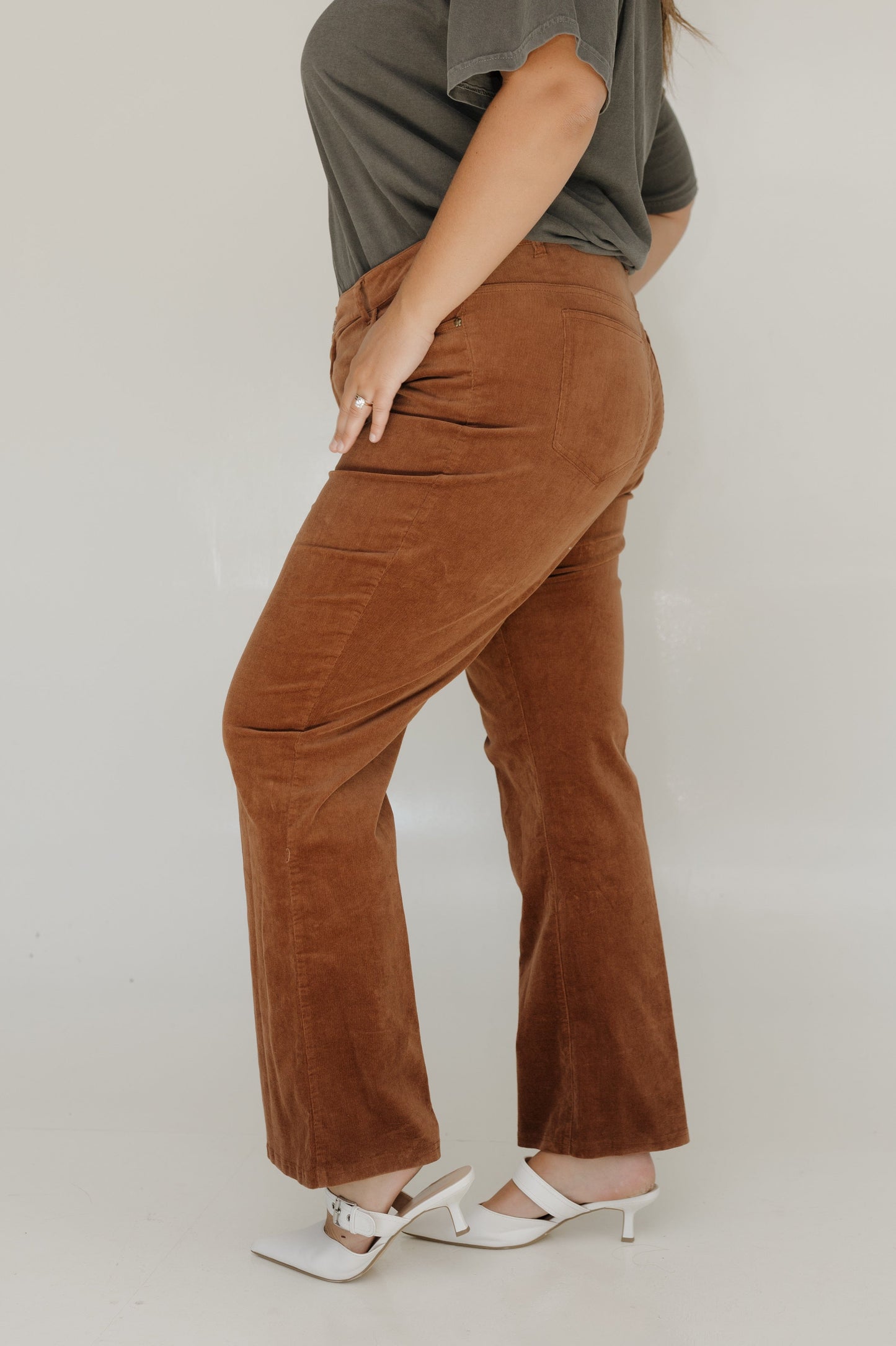 Person wearing brown corduroy pants and a green top on a plain background