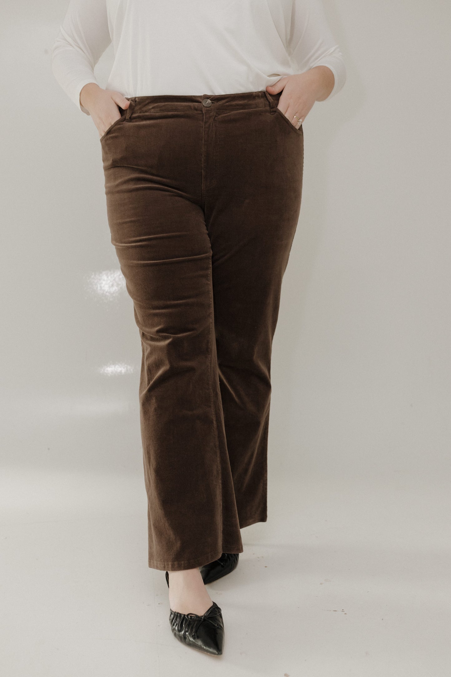 Person wearing brown velvet pants with a plain background