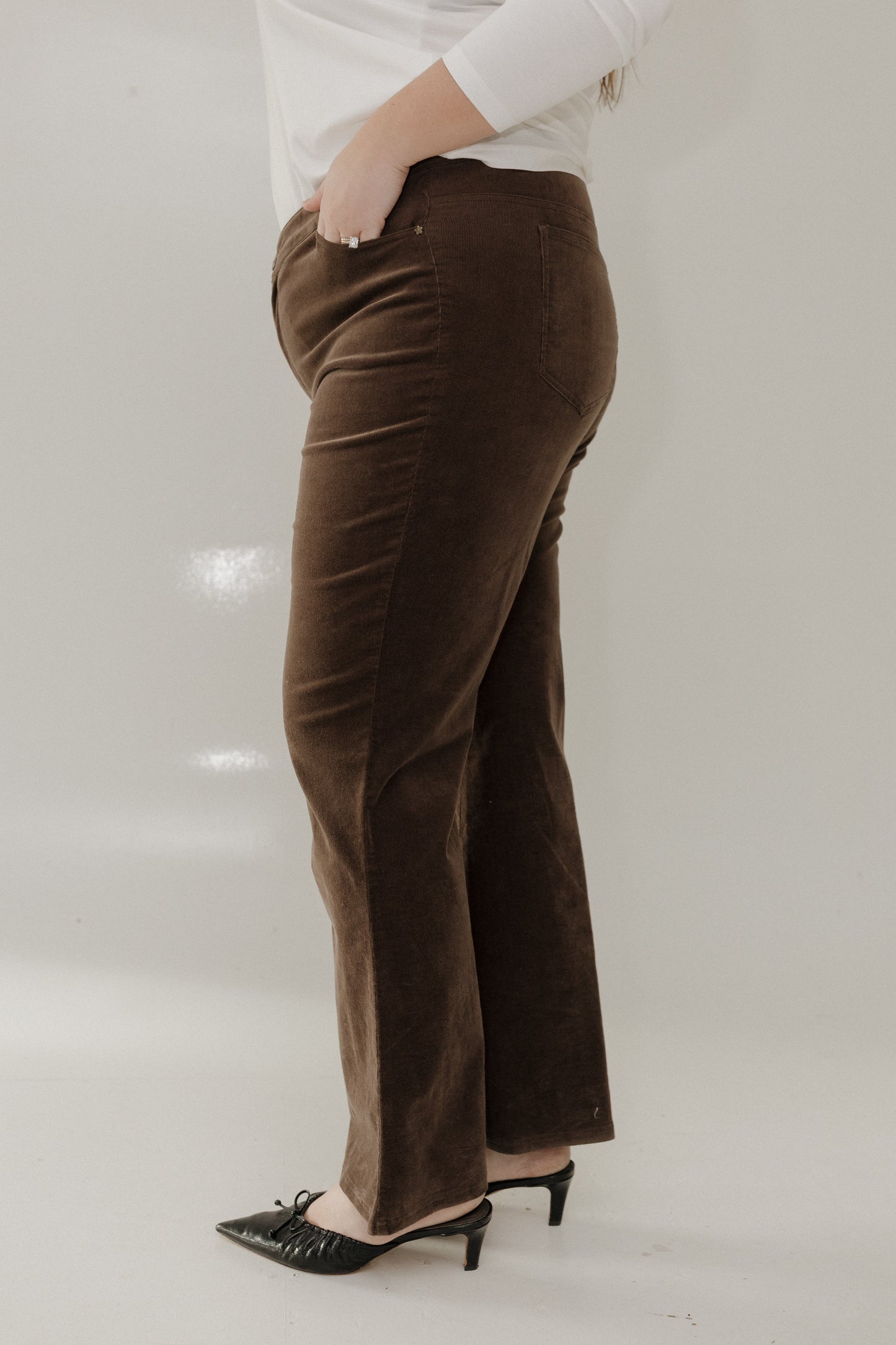 Brown velvet pants worn by a person on a white background