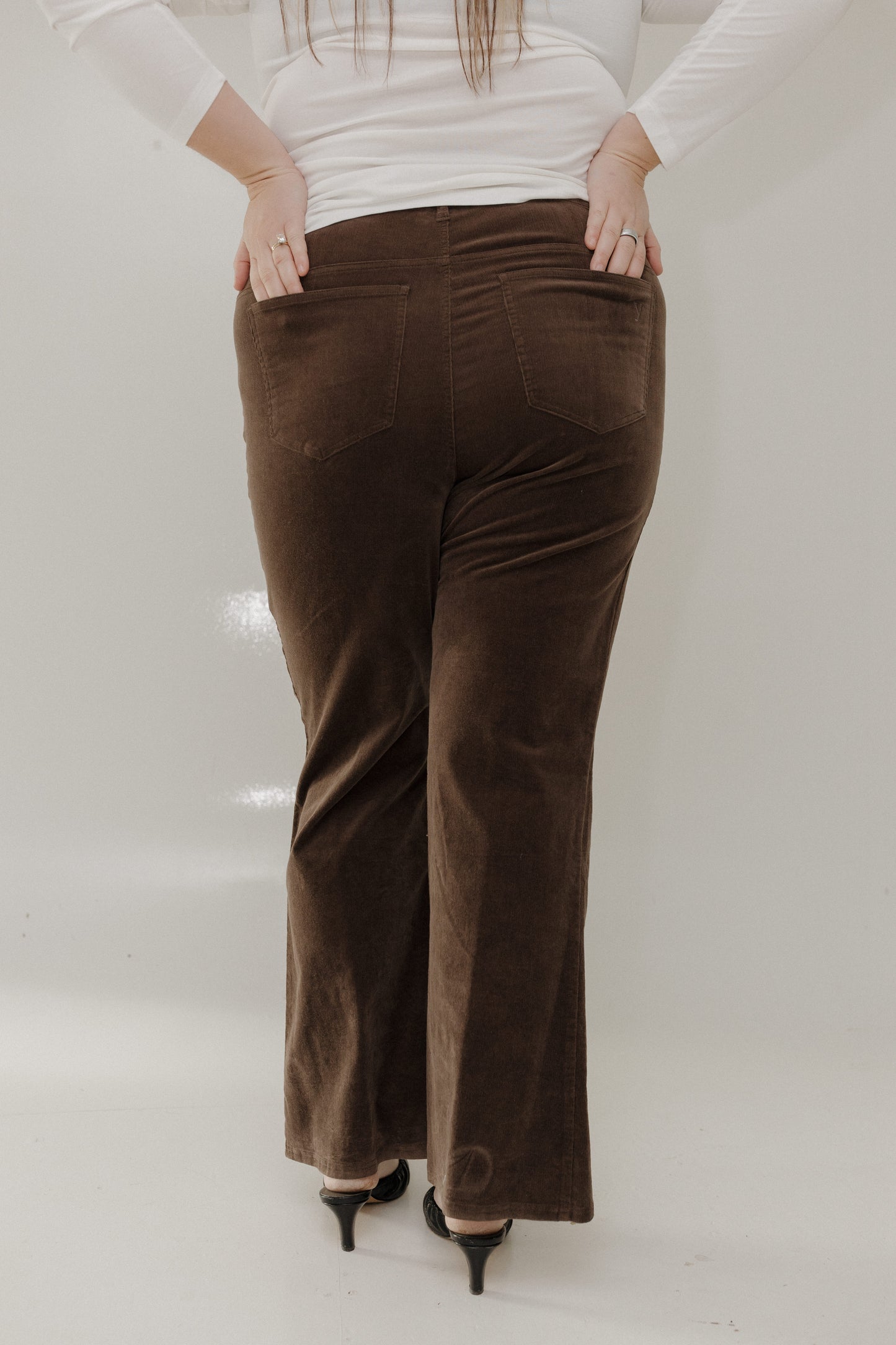 Brown velvet pants worn by a person on a white background