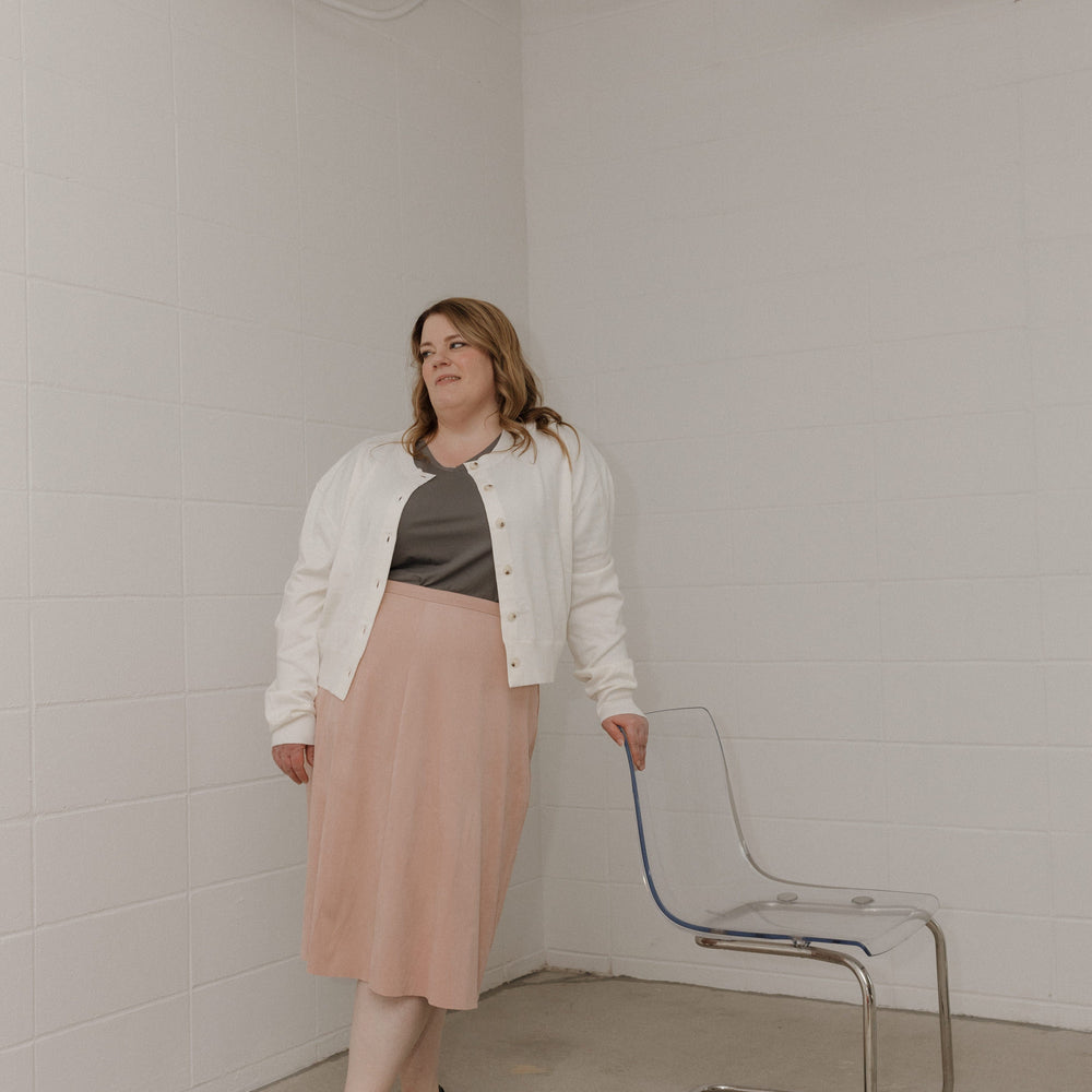 Woman standing in a minimalistic room with a chair and white walls