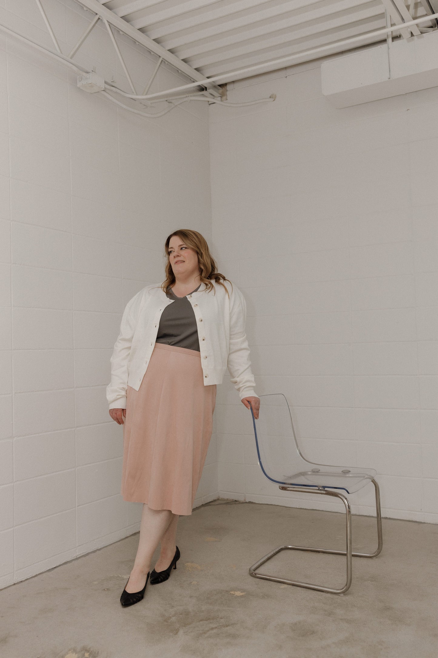 Woman standing in a minimalistic room with a chair and white walls
