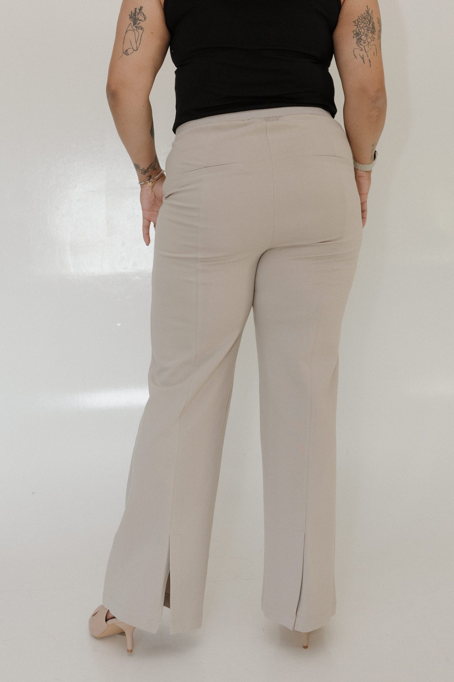 Person wearing beige pants and a black top on a white background