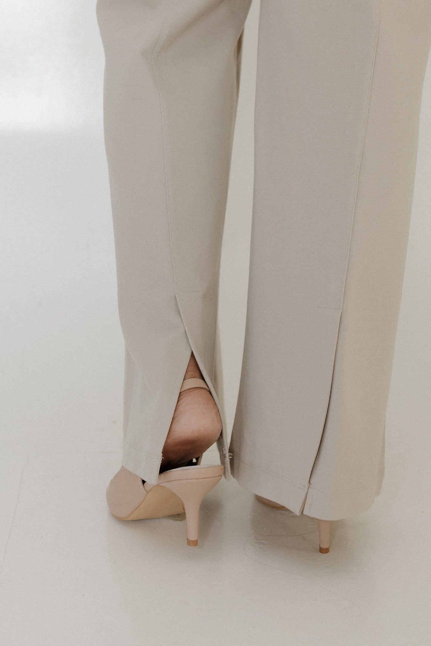 Beige high-heeled shoes and pants on a white background