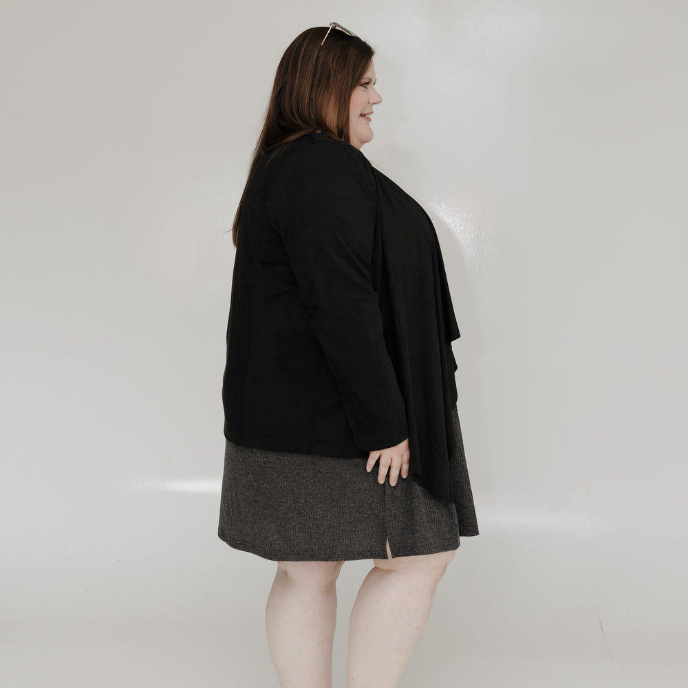 Person wearing a black coat and gray skirt against a white background
