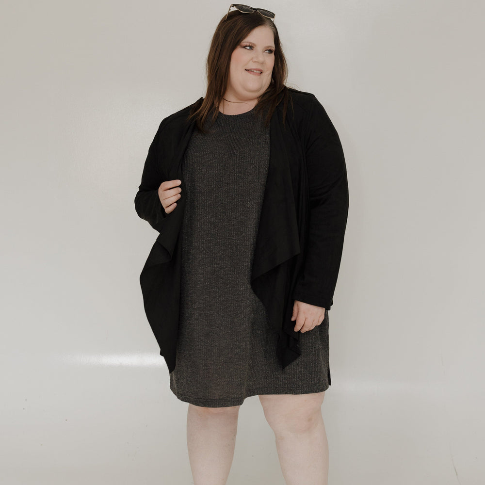 Woman wearing a black coat over a gray dress on a white background