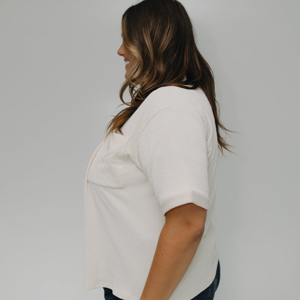Woman wearing a white shirt and blue jeans against a plain background