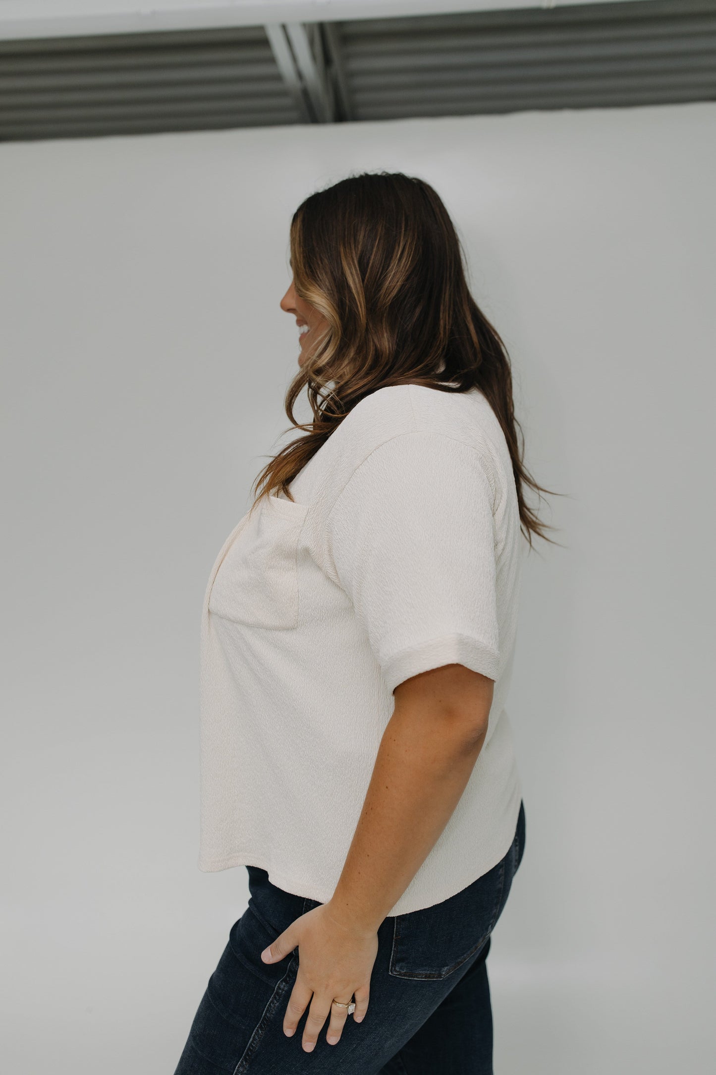 Woman wearing a white shirt and blue jeans against a plain background