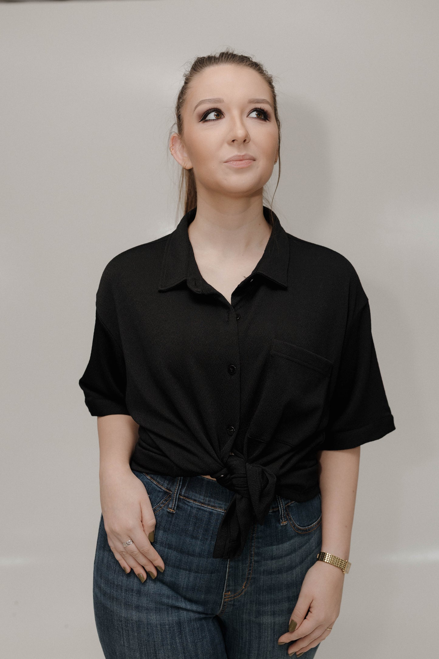 Woman wearing a black shirt and blue jeans against a plain background