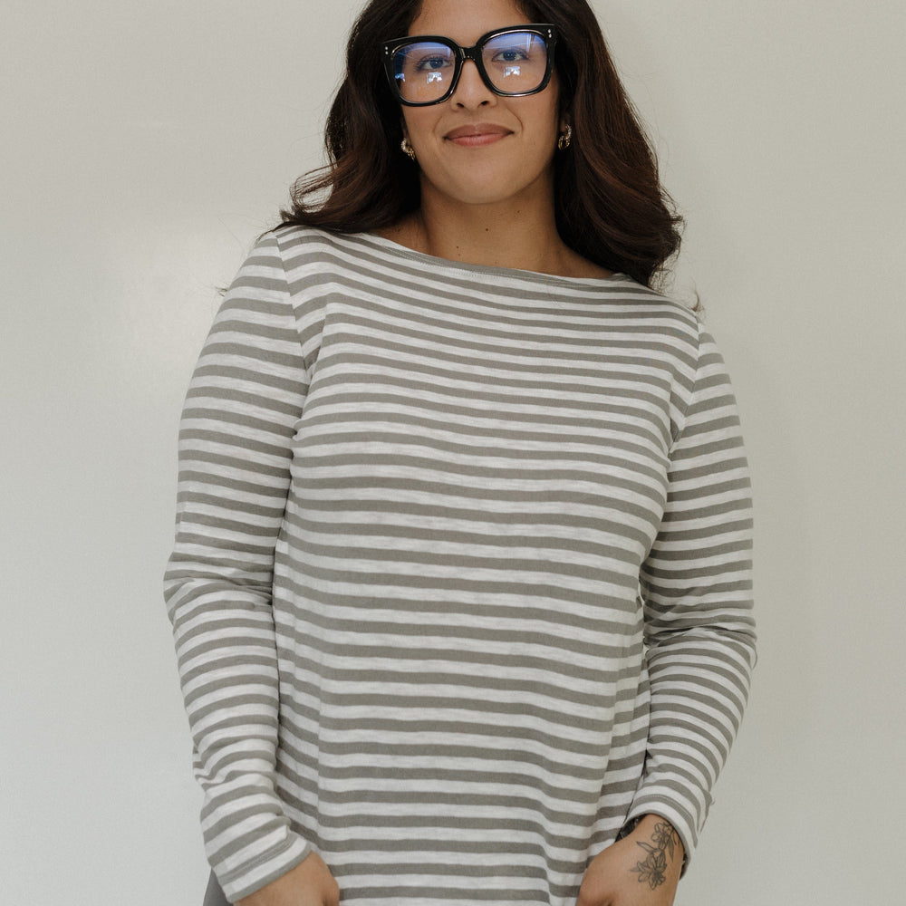 Woman wearing a striped sweater and glasses against a plain background