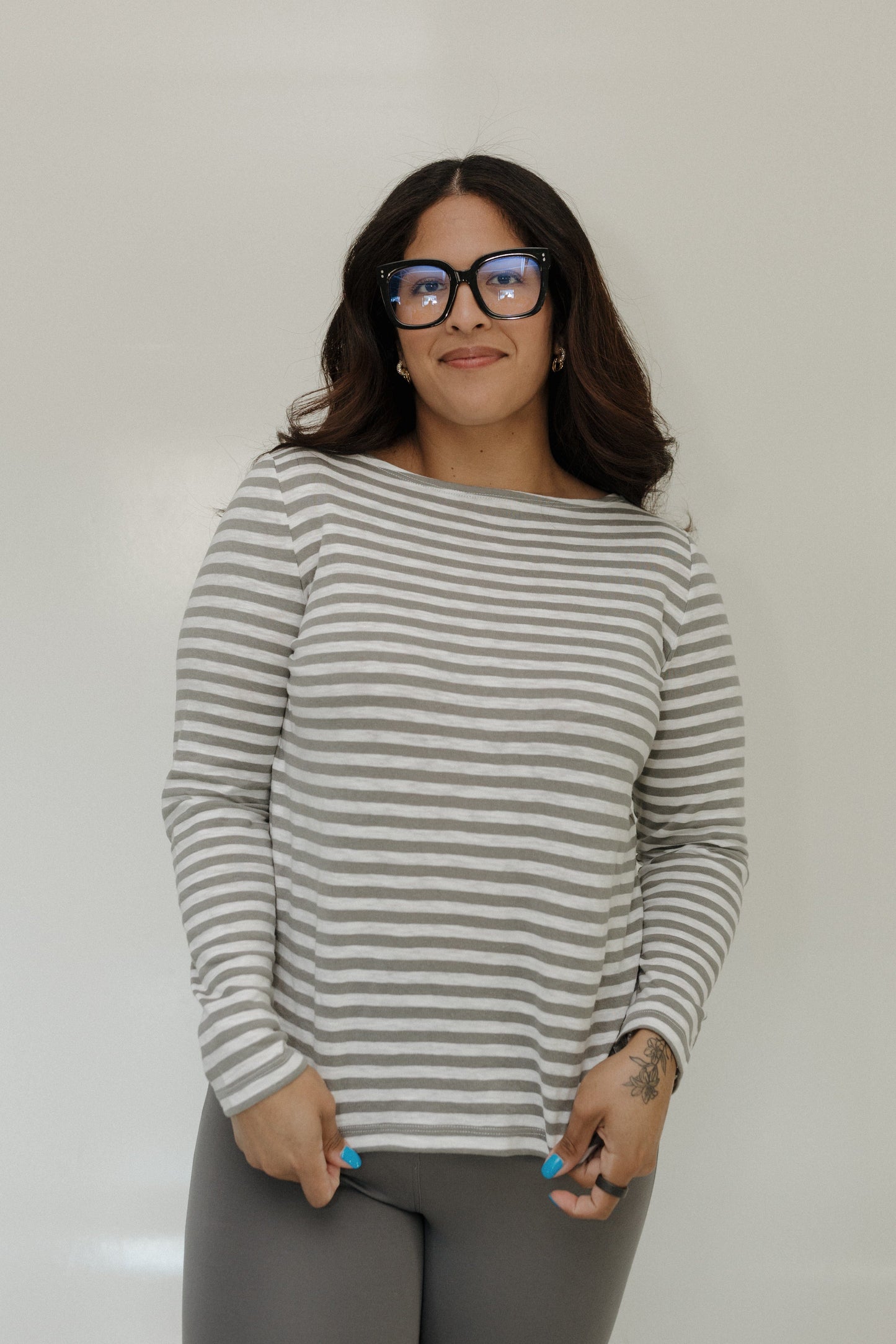 Woman wearing a striped sweater and glasses against a plain background