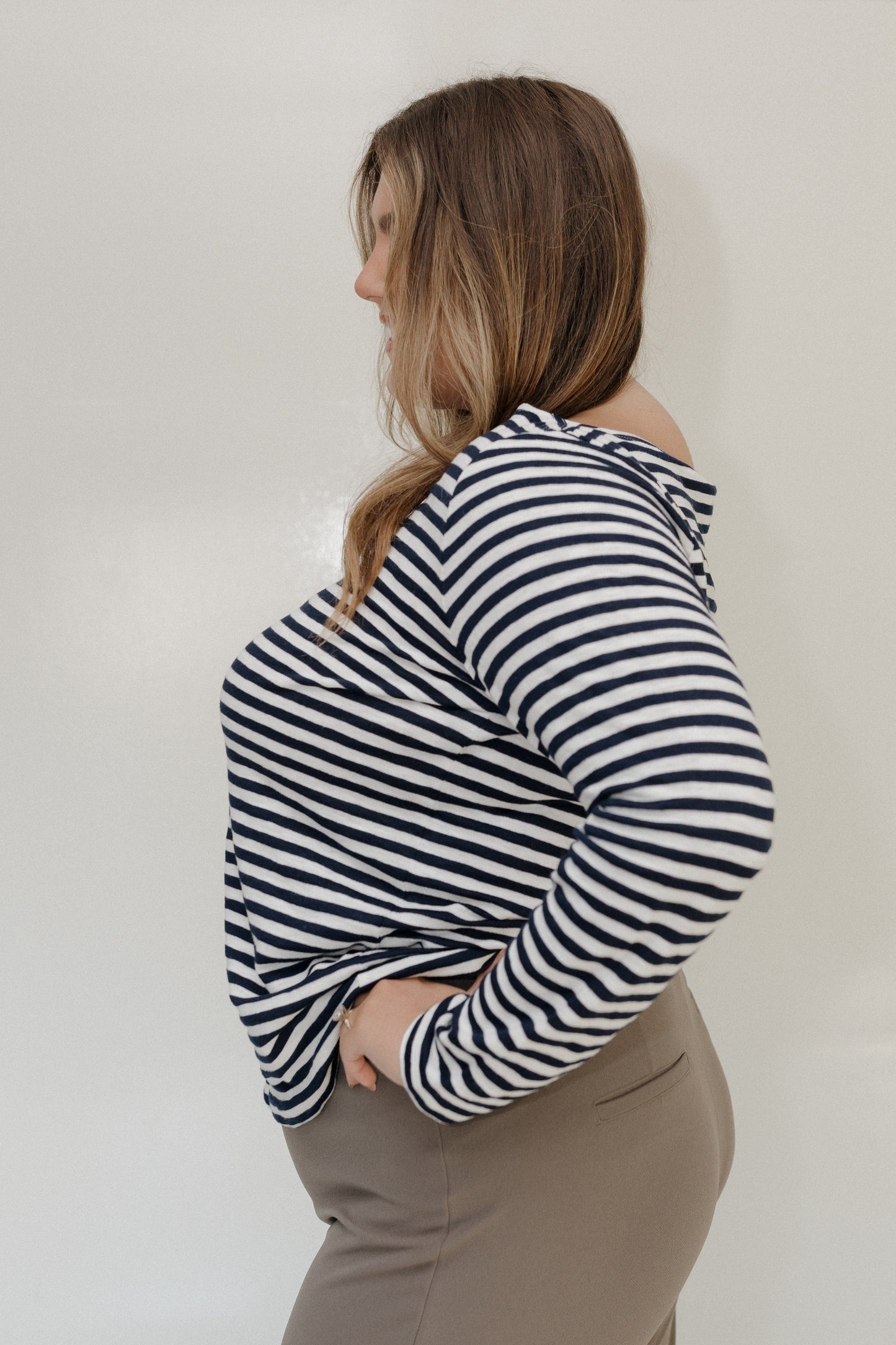 Person wearing a black and white striped hoodie against a plain background