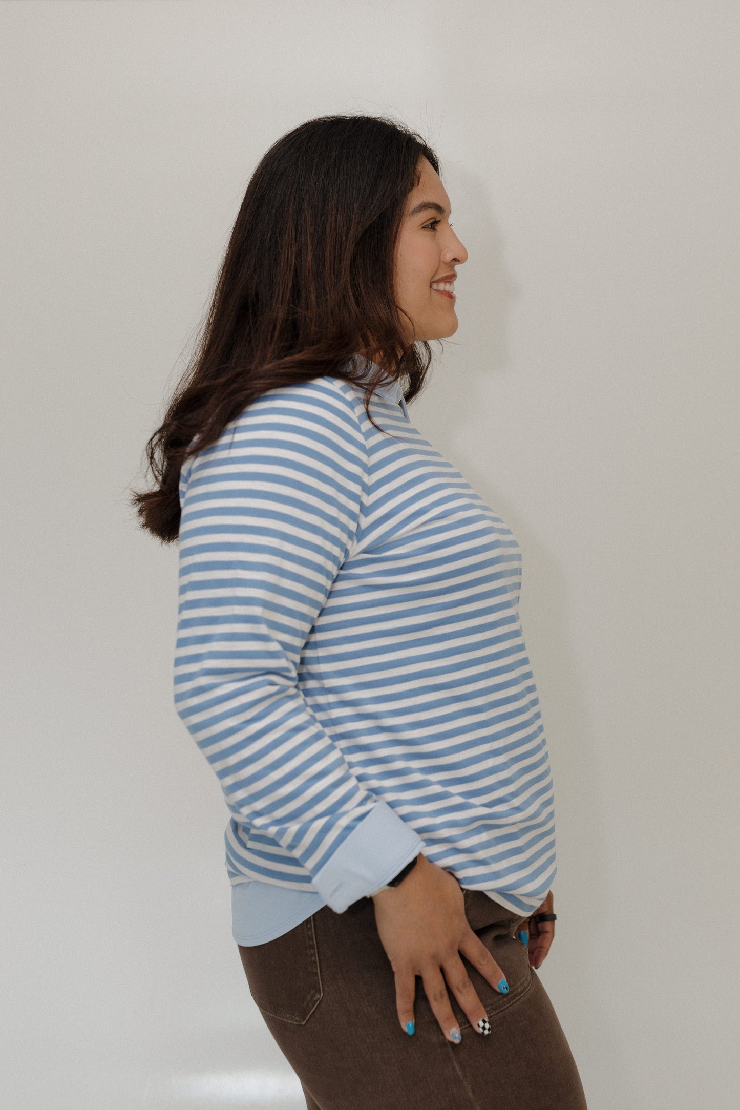 Woman wearing a blue and white striped shirt against a plain background