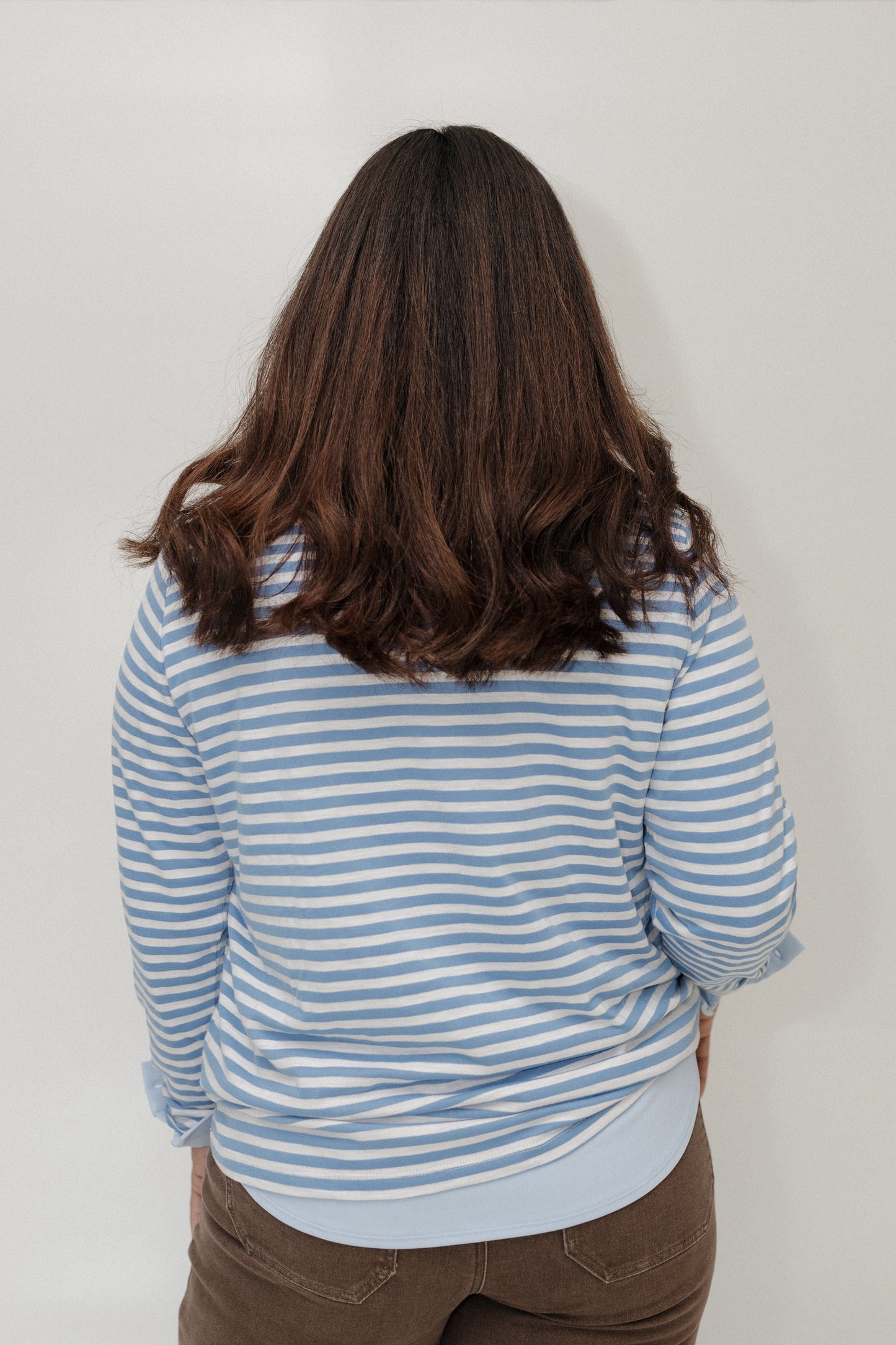 Person wearing a blue and white striped shirt with a plain background