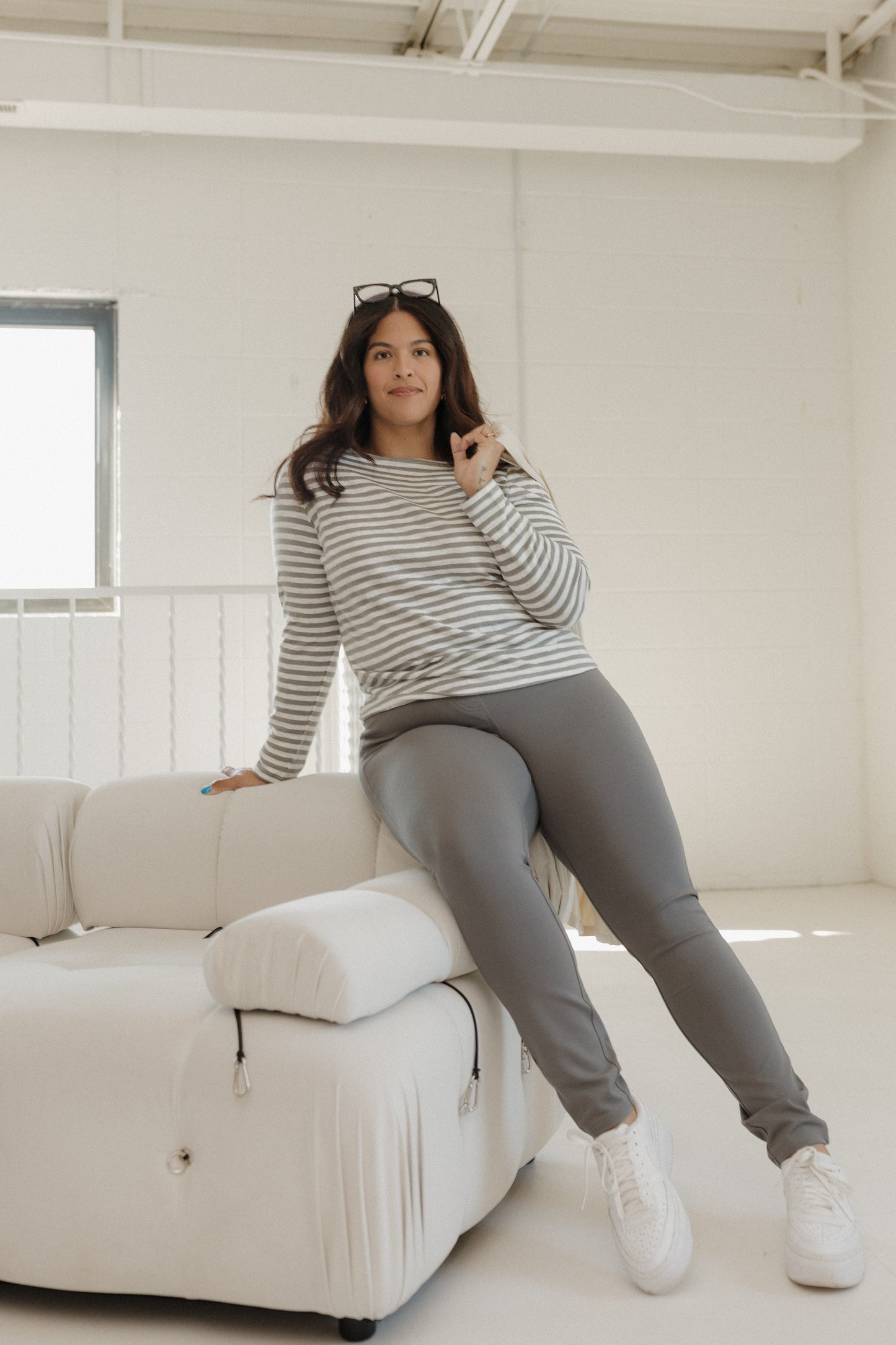 Woman sitting on a white couch in a minimalistic room