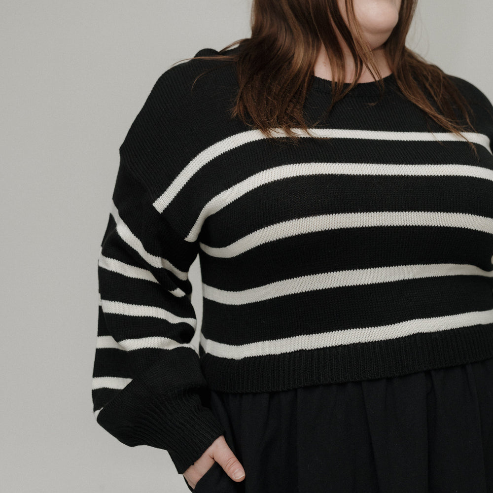 Person wearing a black and white striped sweater against a plain background