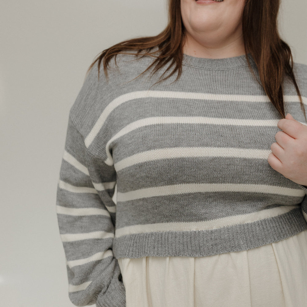 Person wearing a gray and white striped sweater against a plain background