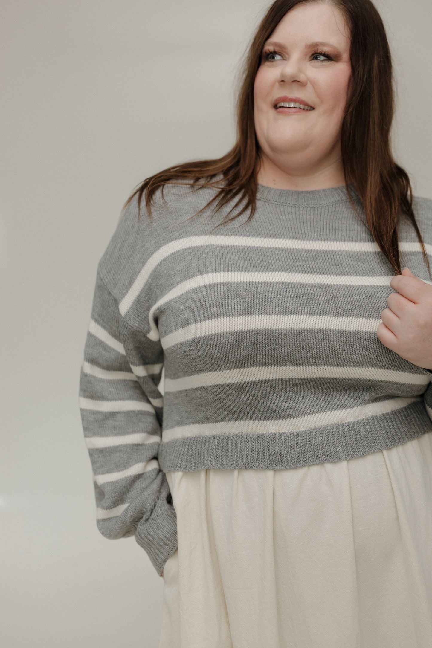 Person wearing a gray and white striped sweater against a plain background