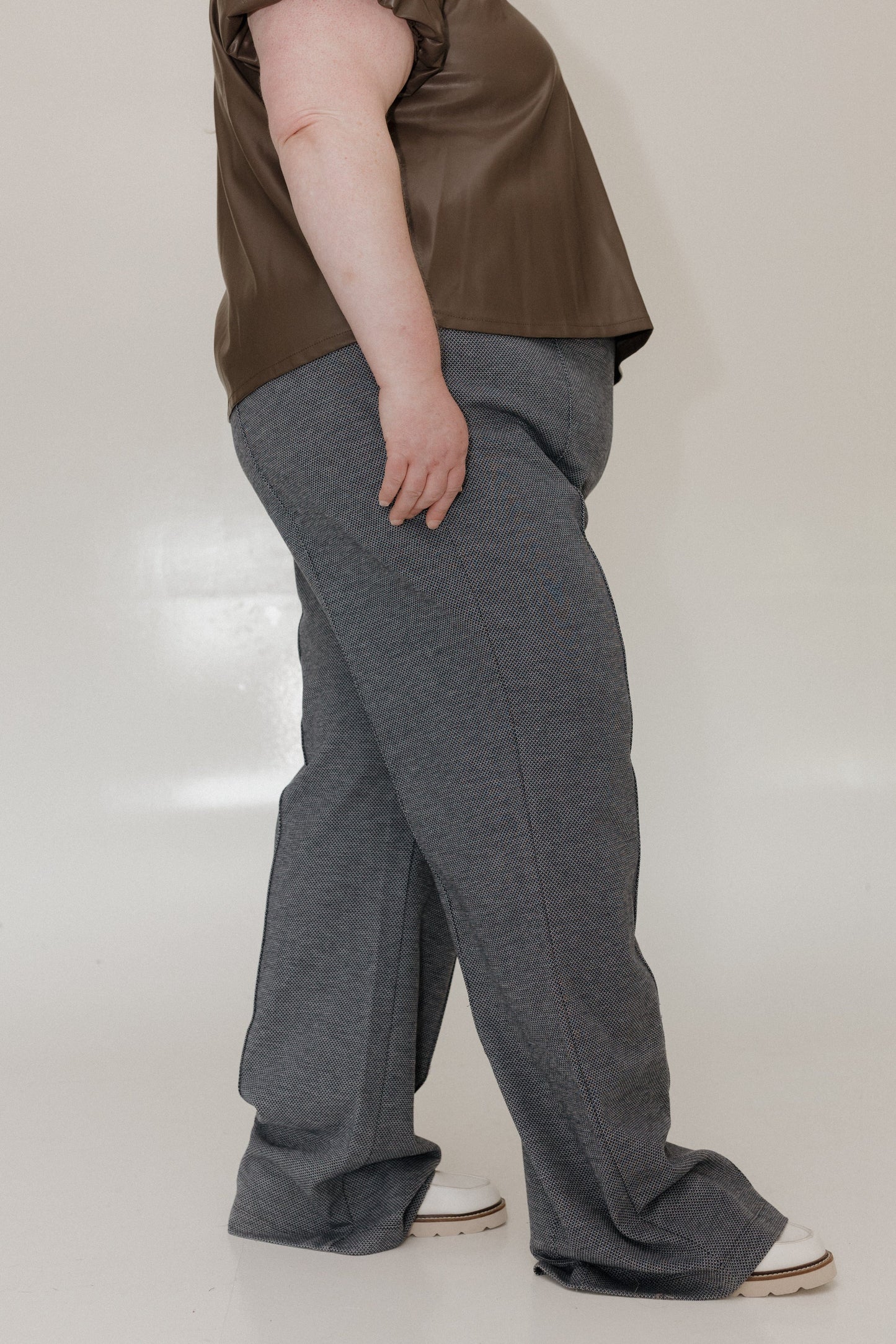 Person wearing a brown top and gray pants on a plain background