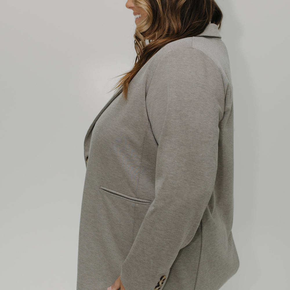 Person wearing a gray blazer against a white background