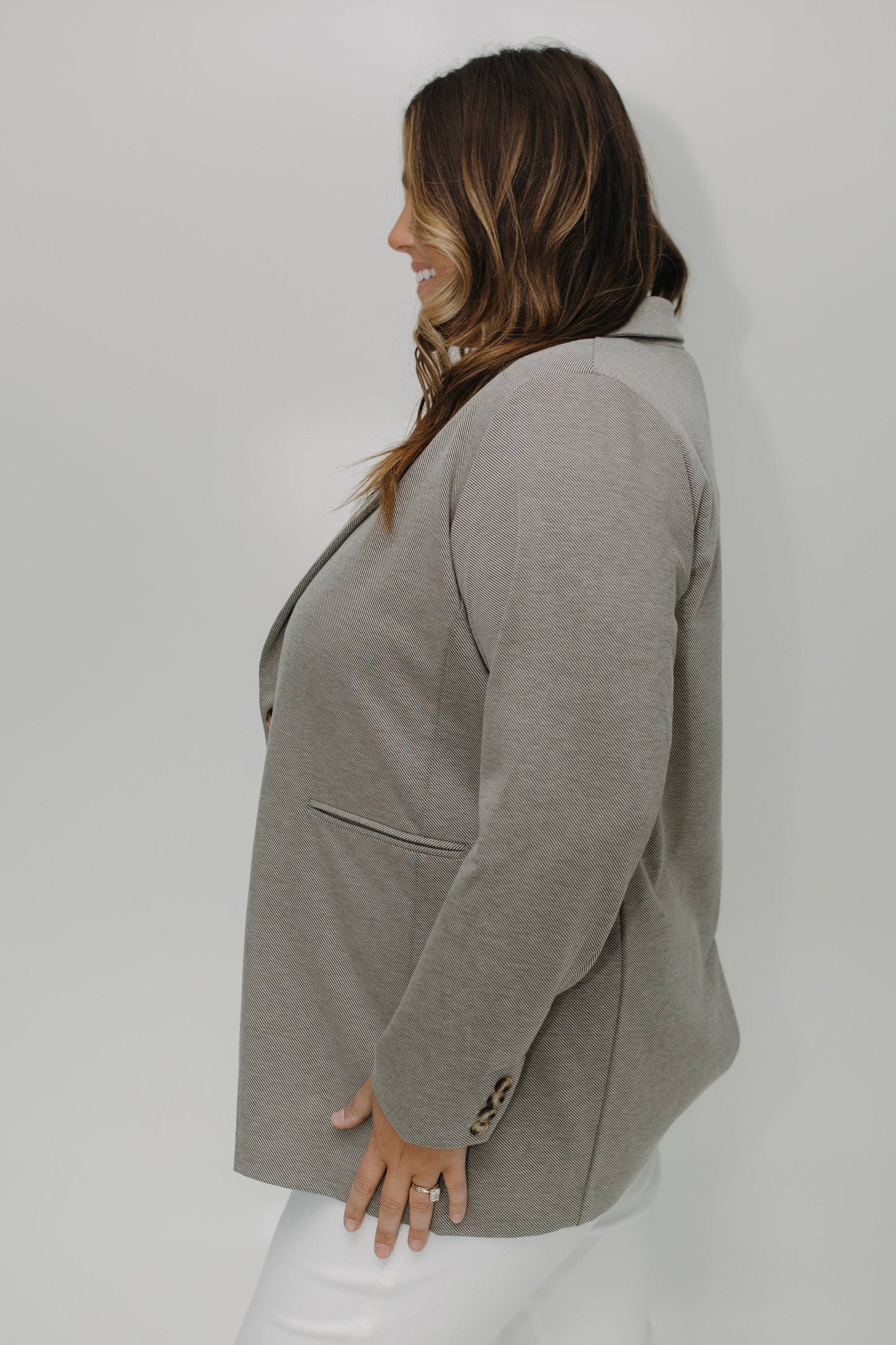 Person wearing a gray blazer against a white background