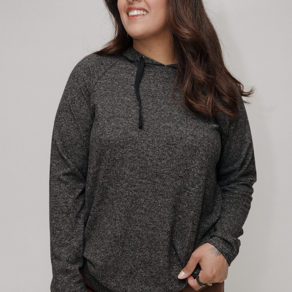 Woman wearing a dark gray hoodie against a plain background