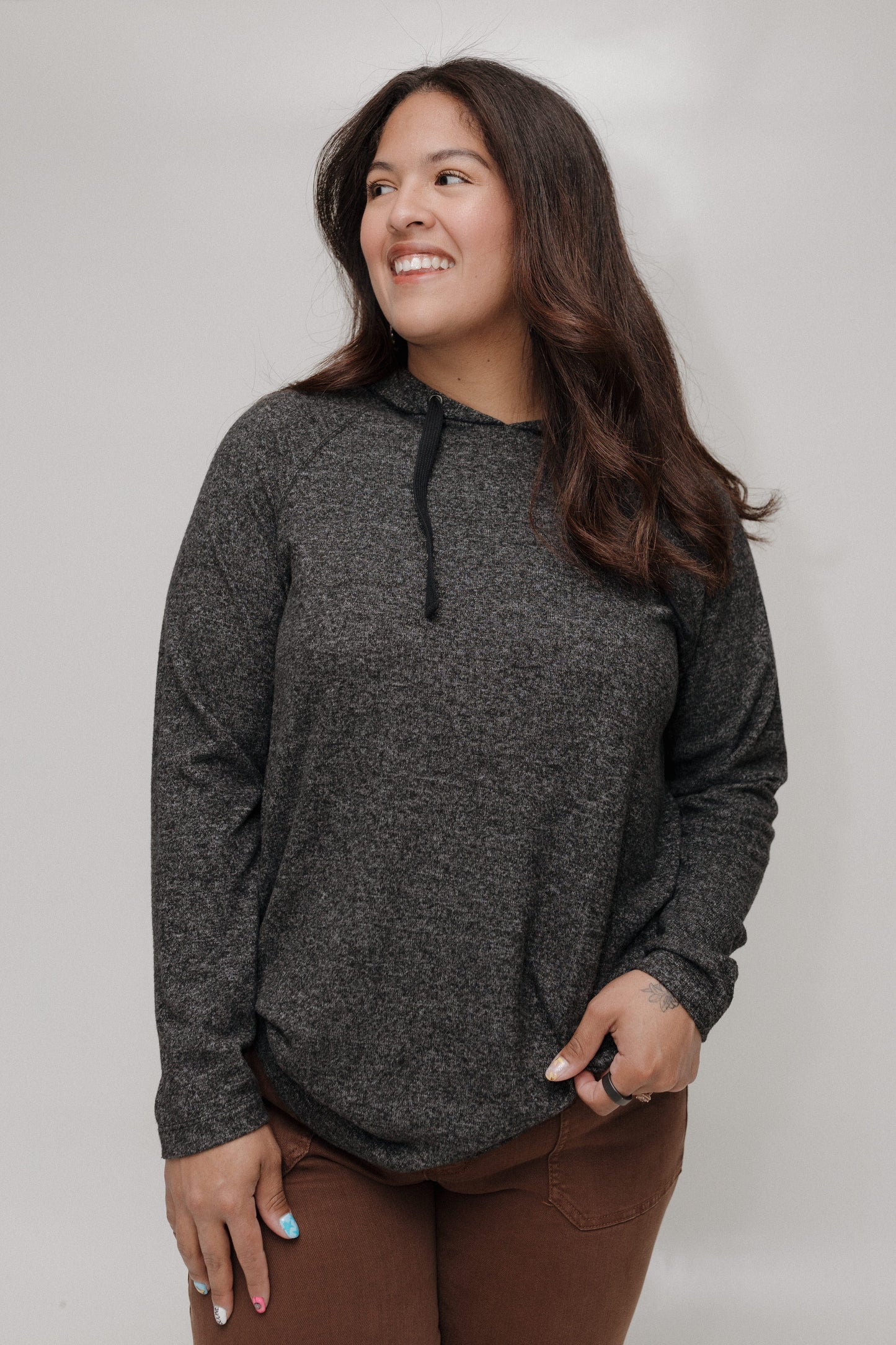Woman wearing a dark gray hoodie against a plain background