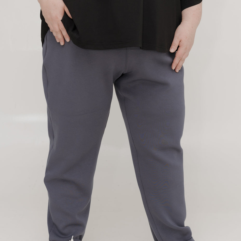Person wearing gray sweatpants and black top on a white background