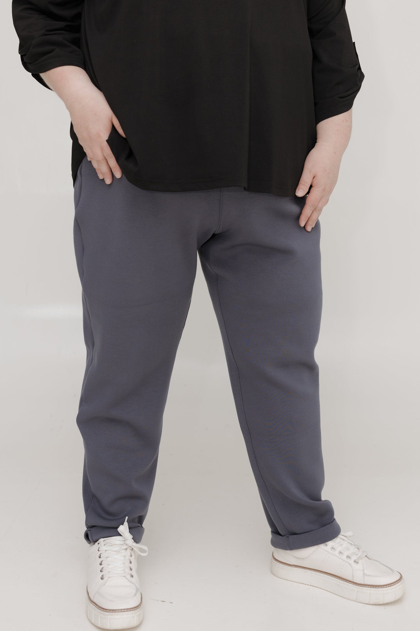 Person wearing gray sweatpants and black top on a white background