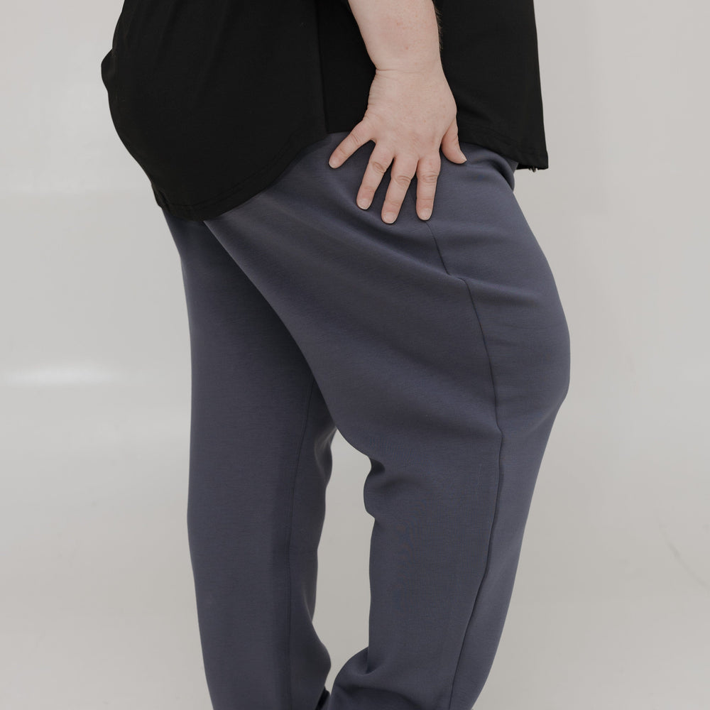 Person wearing a black top and gray pants on a white background