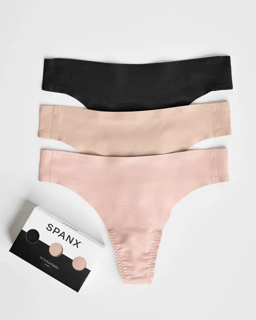 Three pairs of Spanx underwear in black, beige, and pink on a white background with a Spanx packaging box.