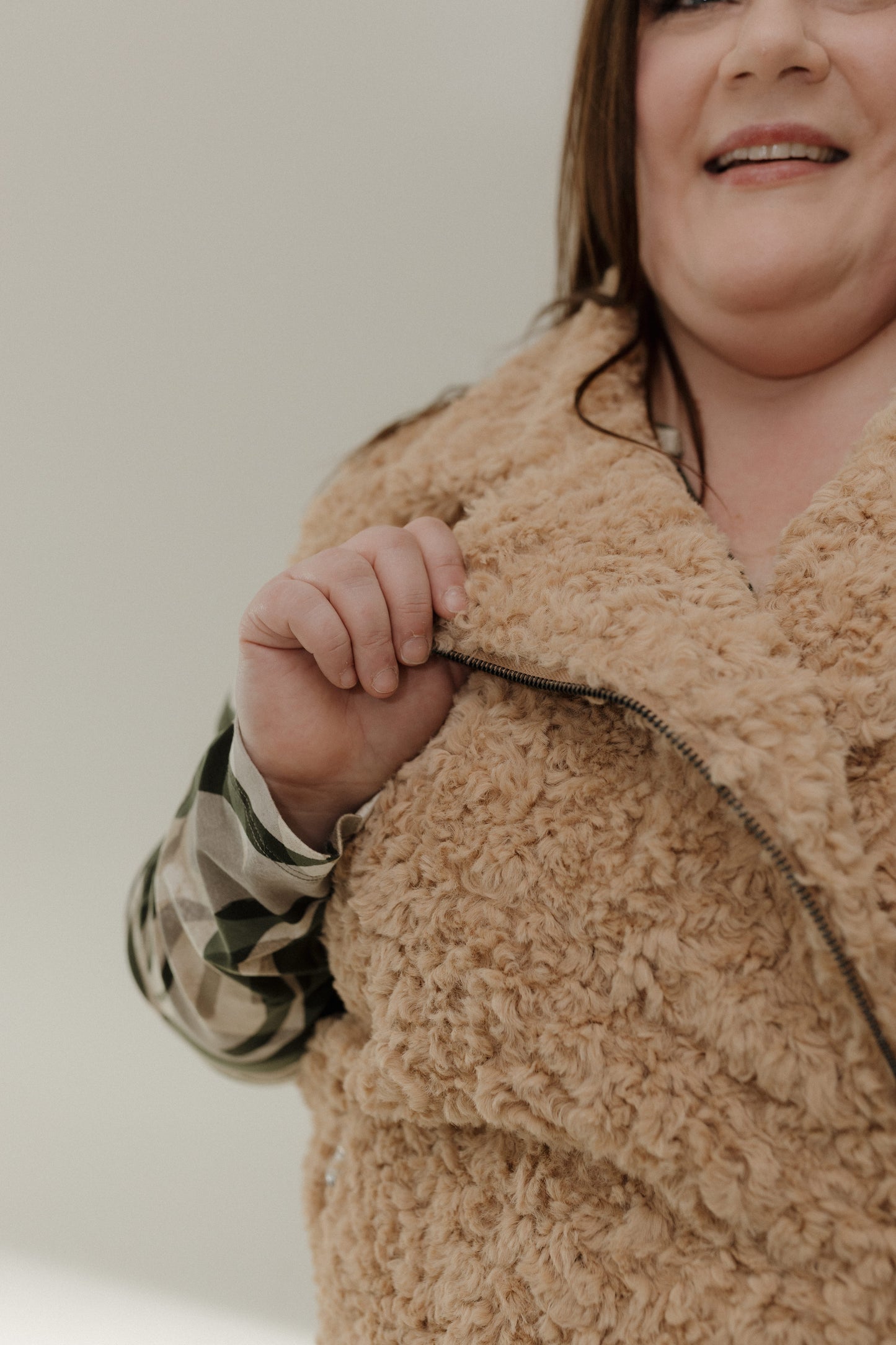 Person wearing a beige sherpa jacket with a neutral background