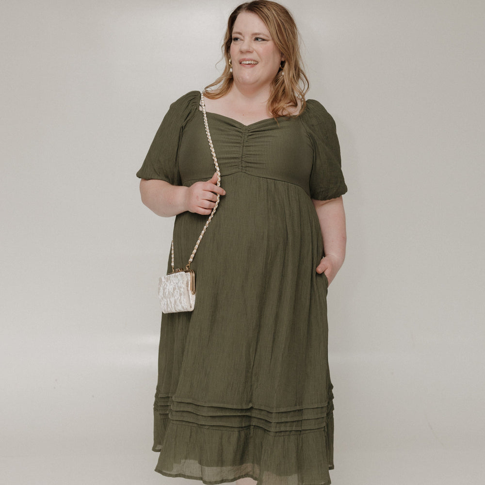 Woman wearing an olive green dress against a white background