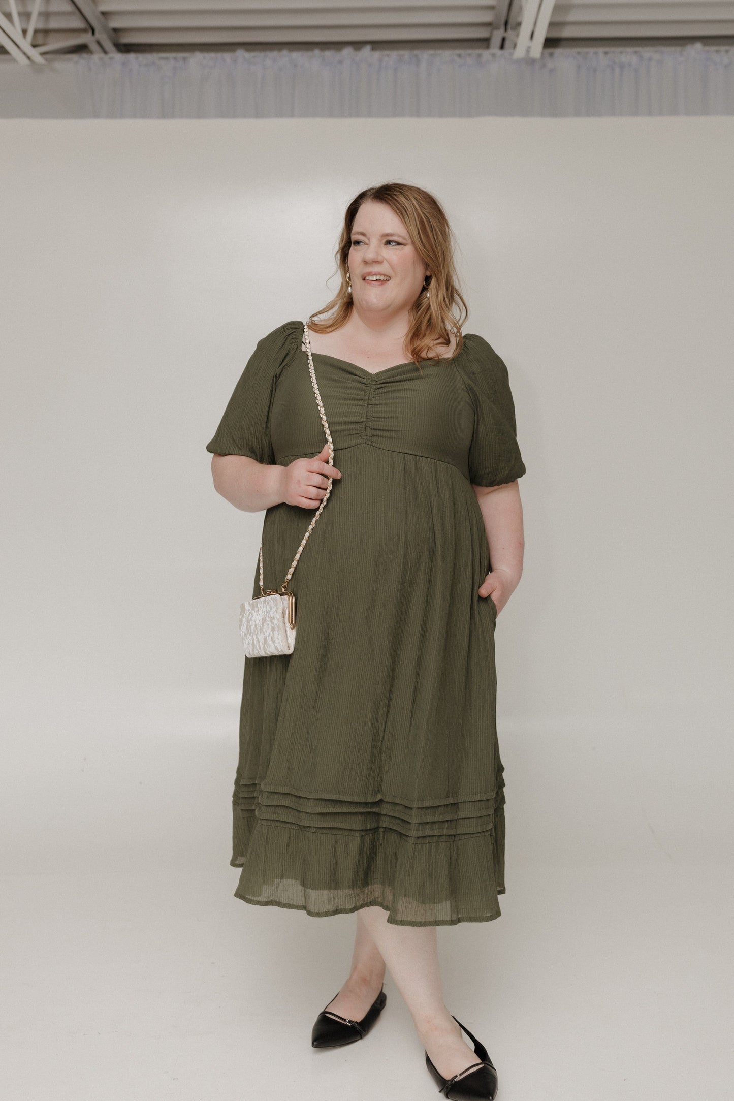 Woman wearing an olive green dress against a white background