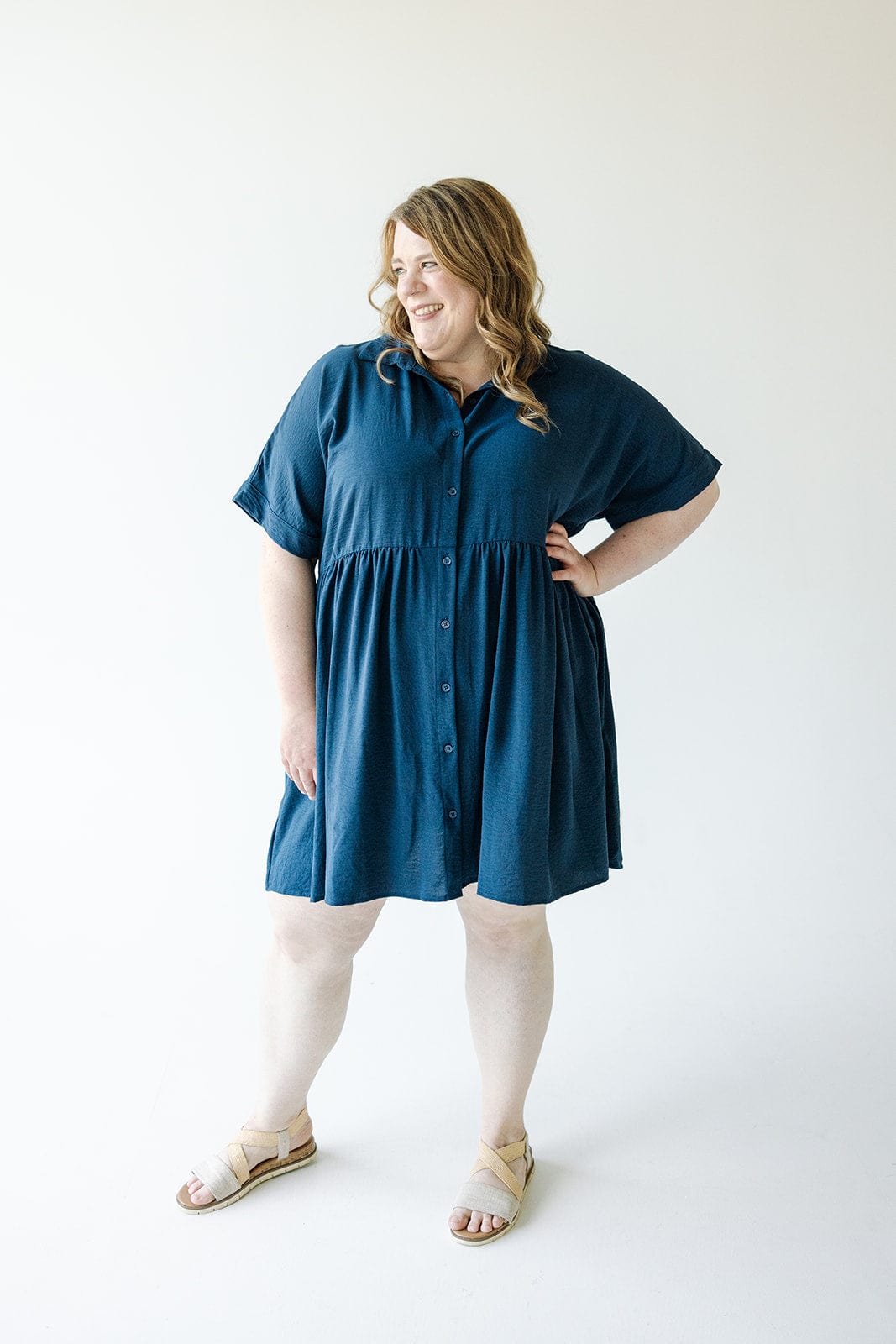 Person in a TEXTURED CHIFFON BUTTON FRONT DRESS IN INK by Mikarose and beige sandals, standing against a plain white background.