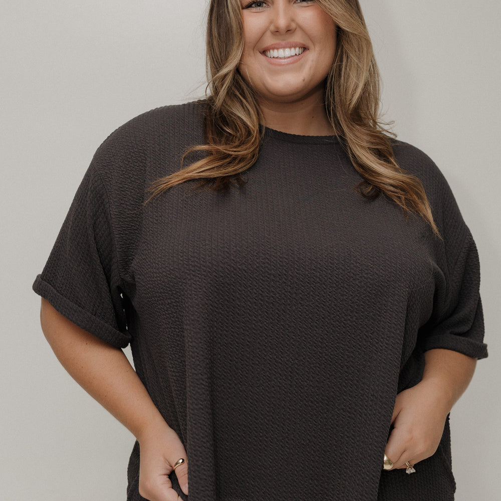 Woman wearing a black oversized t-shirt against a plain background