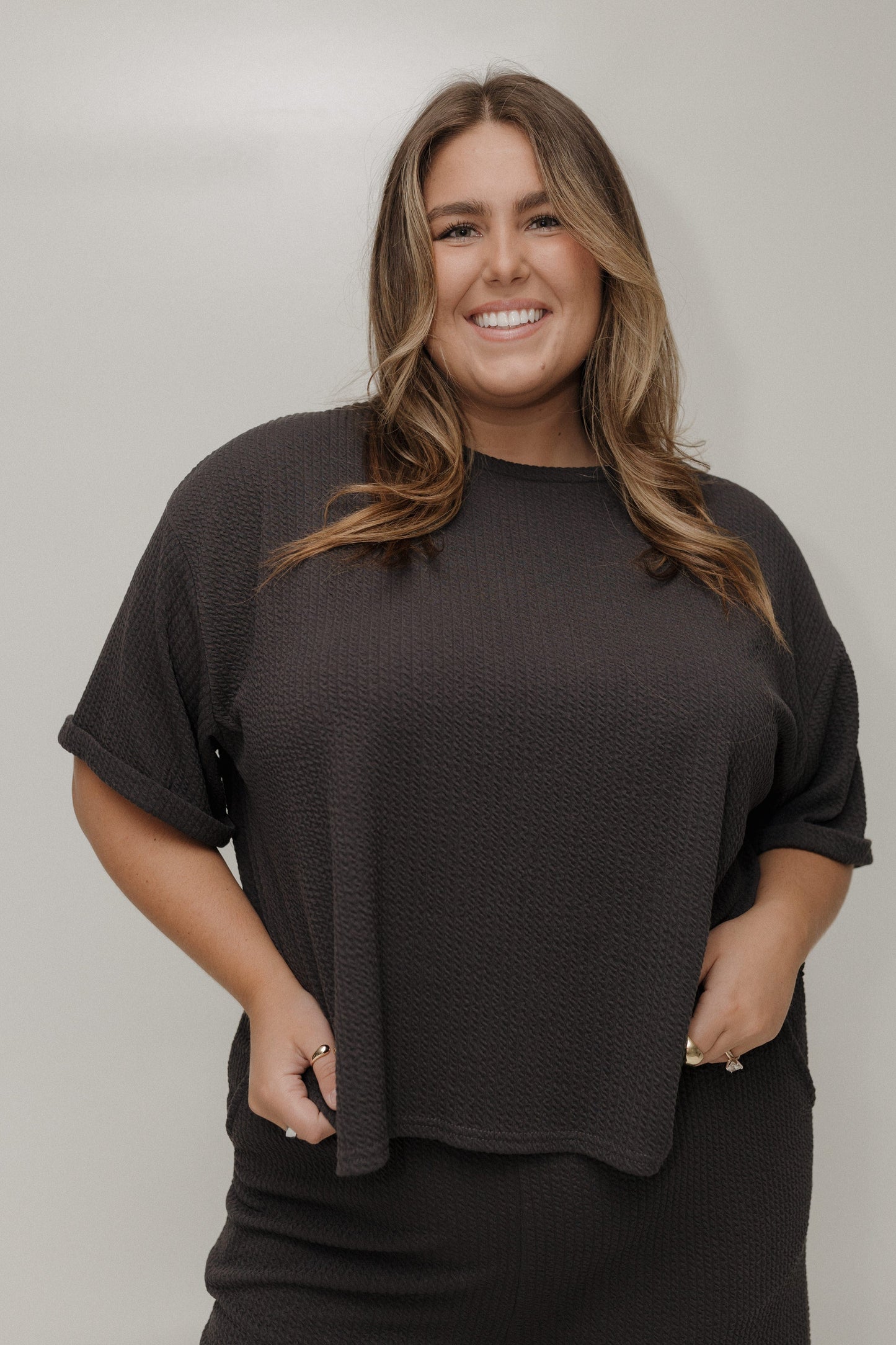 Woman wearing a black oversized t-shirt against a plain background