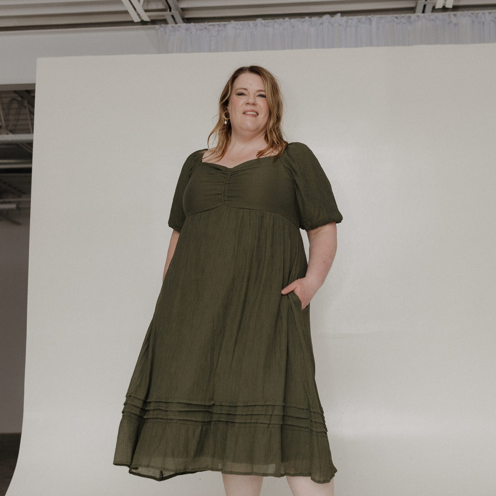 Woman wearing an olive green dress against a white background