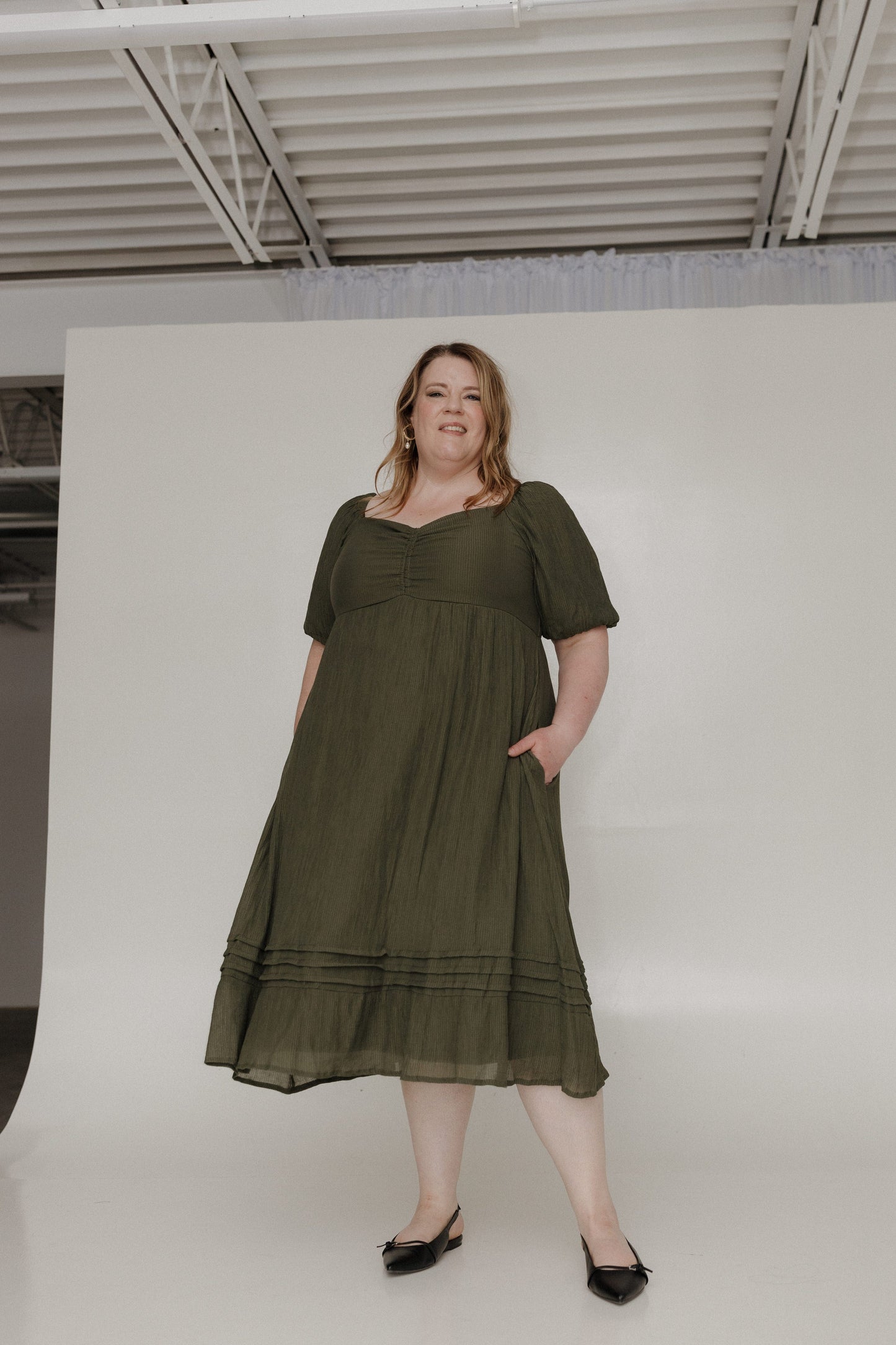 Woman wearing an olive green dress against a white background