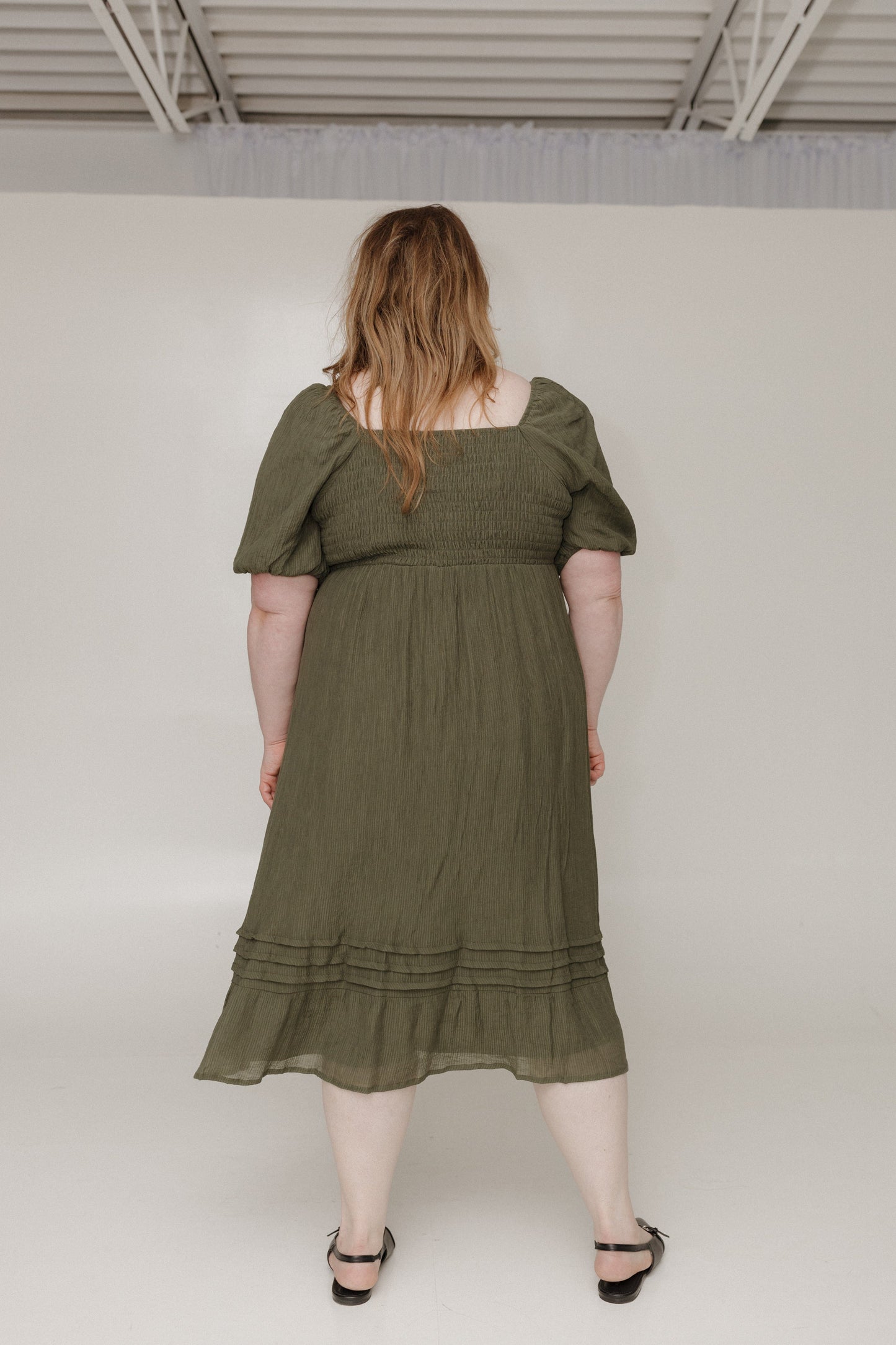 Woman wearing an olive green dress against a white background