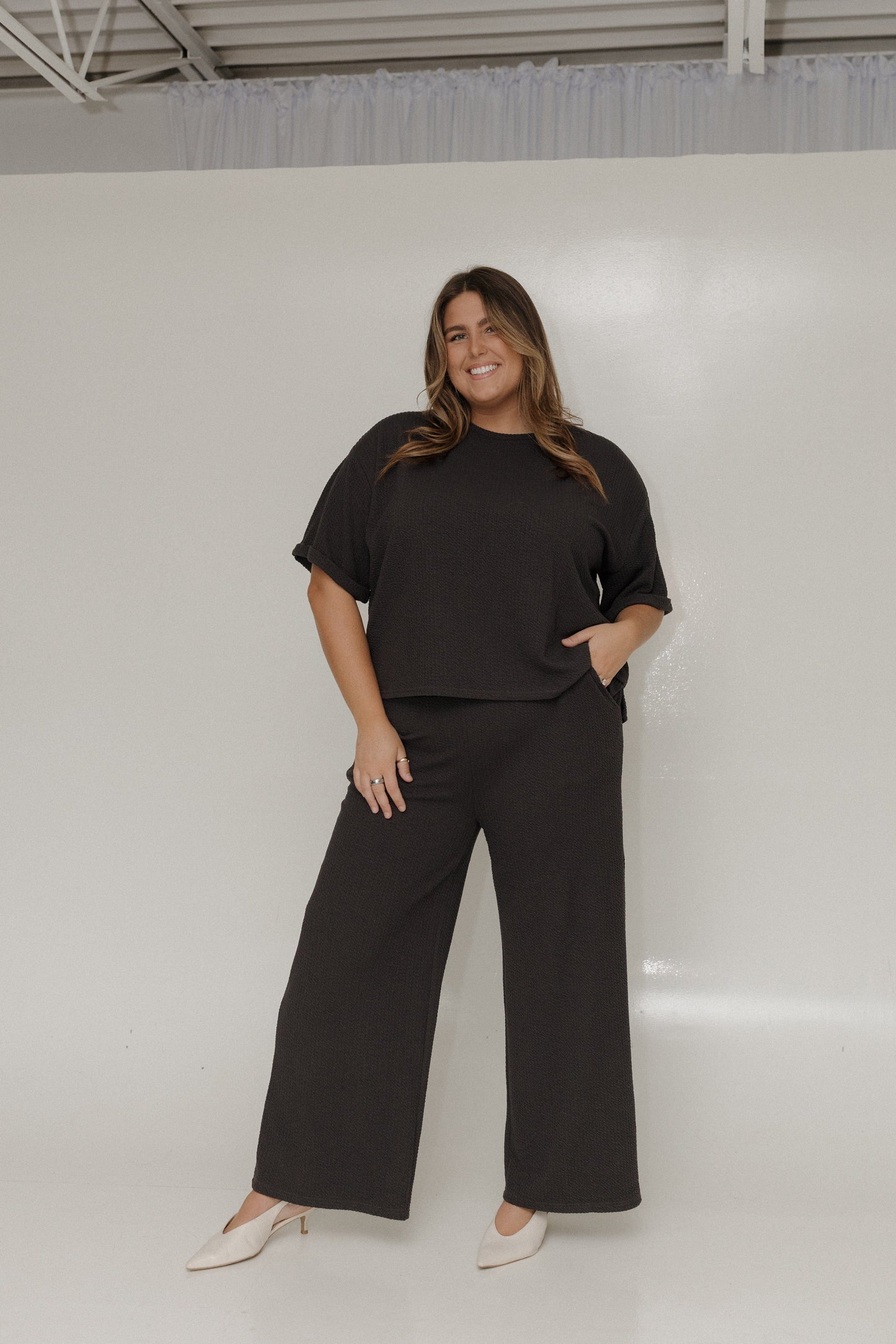 Woman wearing a black outfit standing against a white background