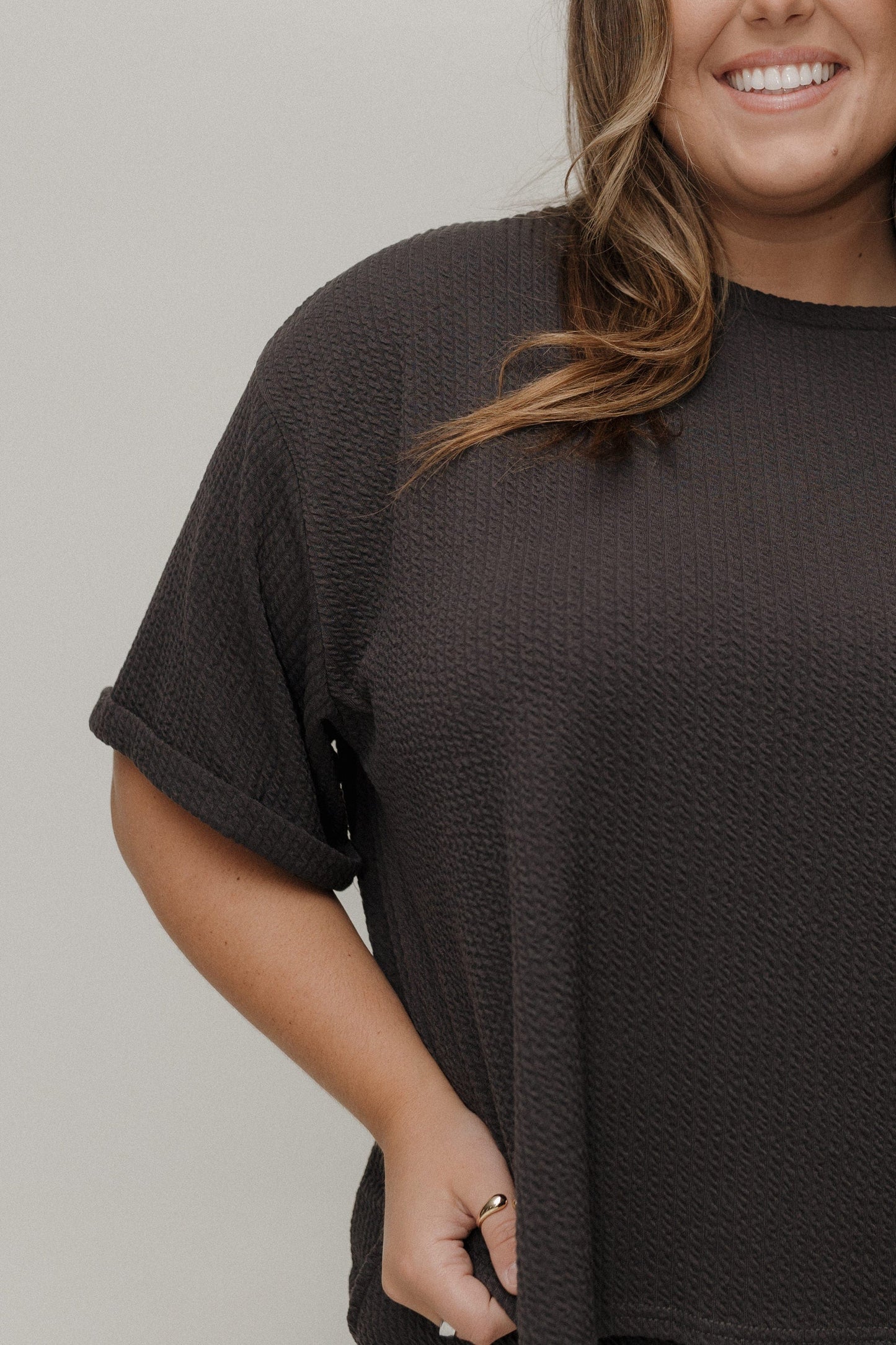 Person wearing a dark brown t-shirt against a plain background