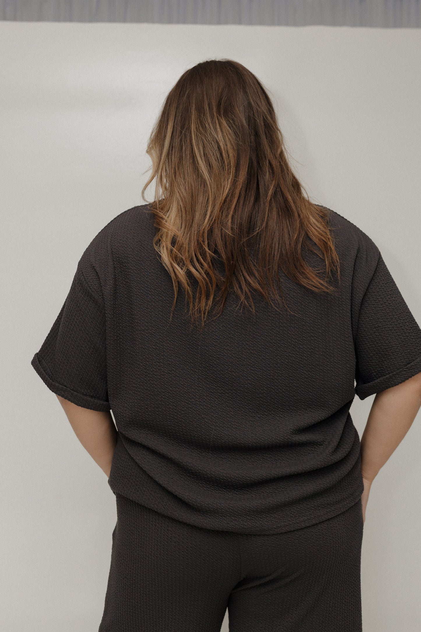 Person wearing a black t-shirt and pants against a plain background