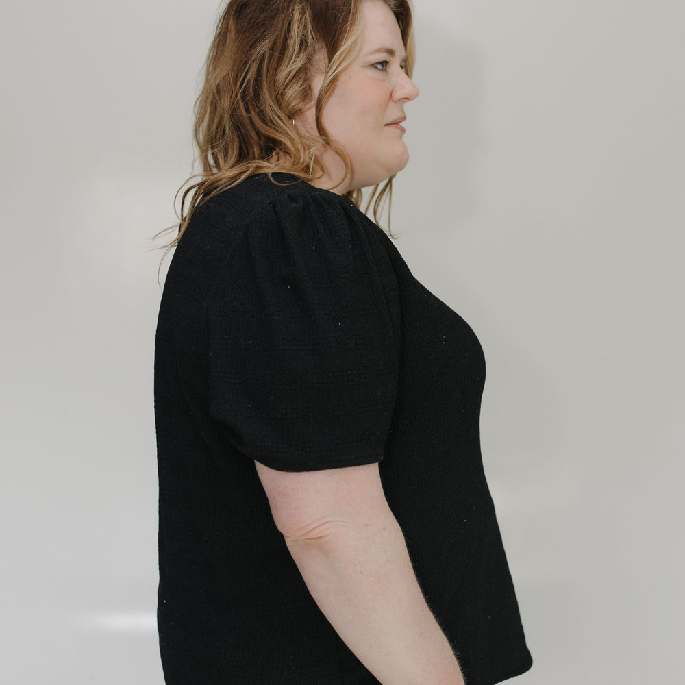Person wearing a black shirt and brown pants against a white background